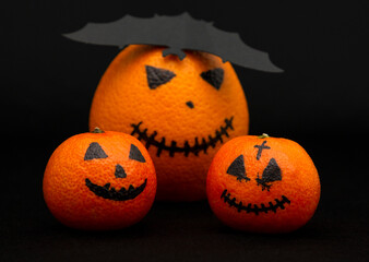 oranges and mandarins painted like a halloween pumpkin, happy halloween citrus