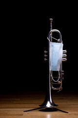 A silver plated piston trumpet with a medical mask on, to represent restrictions on concerts and...