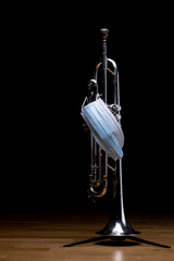 A silver plated piston trumpet with a medical mask on, to represent restrictions on concerts and...