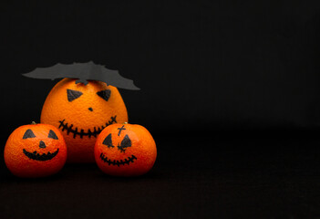 oranges and mandarins painted like a halloween pumpkin, happy halloween citrus