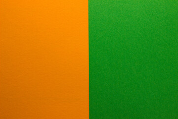 Fototapeta premium Background of two vertical rectangles green and orange. Sheets of blank green and orange paper with fine texture, split vertically, close up.