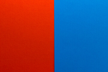 Background of two vertical rectangles red and blue. Sheets of blank red and blue paper with fine texture, split vertically, close up.