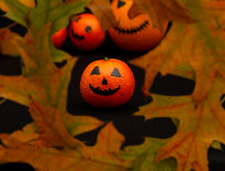 orange mandarin painted like a halloween pumpkin in foliage happy halloween citrus