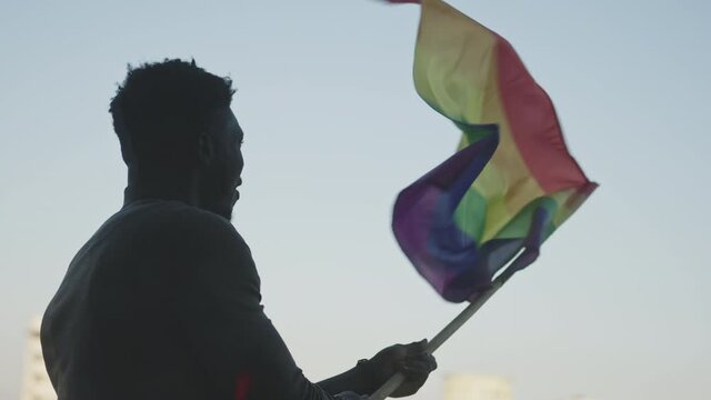 Black man waving rainbow flag. Sexual identity and equal treatmant concept. High quality 4k footage
