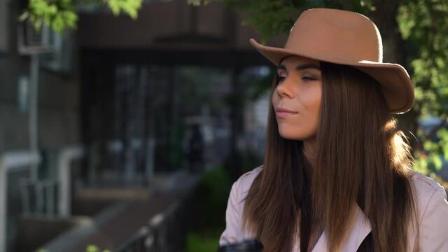 young beautiful woman in a felt hat drinks aromatic coffee from a disposable cup. High quality 4k footage