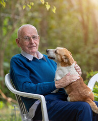 Senior man cuddling dog in garden