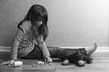 A sad teenage girl sits at home next to tablets, a teddy bear and a phone. Children's depression...
