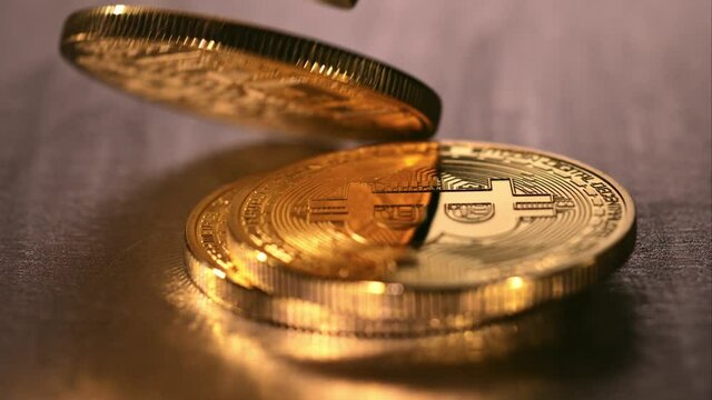 Slow motion shot of bitcoins falling onto a steel surface. 