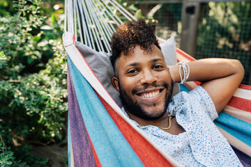 Portrait of smiling black man relaxing in hammock in back yard