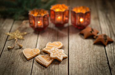 Homemade Christmas gingerbread on wooden rustic table. Burning candles in background. Traditional autumn and winter home scene. Close-up