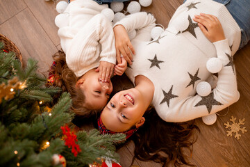 Two children sister girls lie next to a Christmas tree view from above, space for text