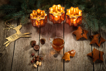 Homemade Christmas mulled wine punch with gingerbread, nuts and sweets on wooden rustic table. Burning candles in background. Traditional autumn and winter hot drink. Close-up