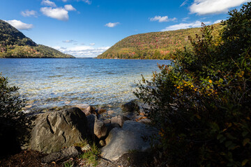 Autumn trees under a blue sky line the shores of Long Pond on an autumn day in Acadia National Park, Maine