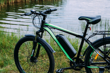 E-bike in the park in summer day. The view of the e motor and power battery.