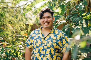 Portrait of happy, smiling latinx man in bright patterned shirt standing outside in garden