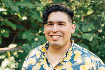 Portrait of happy, smiling latinx man in bright patterned shirt standing outside in garden