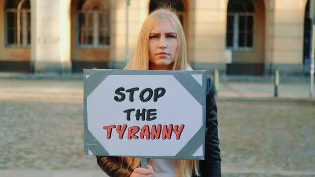 Young woman calling to stop the tyranny by holding steamer. Protest walk in the city center.