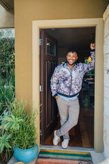 Portrait of handsome, happy, smiling young man in a floral jacket standing in the doorway of his home. 