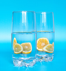 glasses of water and the reflection of lemons through the glass on a blue background