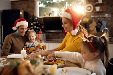 Smiling woman eating Christmas lunch with her family in dining room.