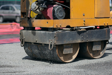 Fototapeta na wymiar Small road roller during asphalt concrete pavement compaction repairing works 