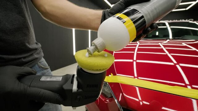 Worker polish a red car. Car detailing - Men are using machinery car polishers maintenance to remove marks repair according to the surface of the car's paint before contin