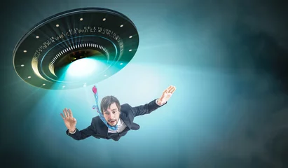 Foto auf Acrylglas UFO Entführungskonzept durch Außerirdische. Junger Mann wird von UFO entführt.