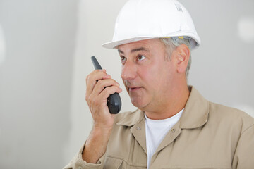 male builder in hardhat with walkie talkie