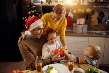 Happy family having fun while opening Christmas presents at home.