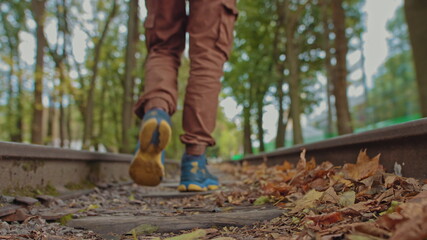 A handsome young man of 18 years in modern warm clothes with a backpack on his shoulders walks on the track, the camera is out of focus. The concept of adolescent loneliness, one in the whole world