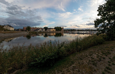 Fototapeta na wymiar Lake and city embankment under the evening cloudy sky