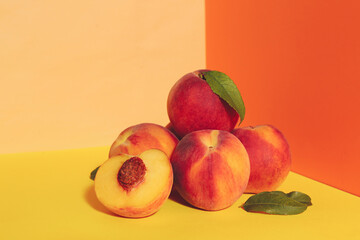 Fresh ripe peaches and green leaves on color background