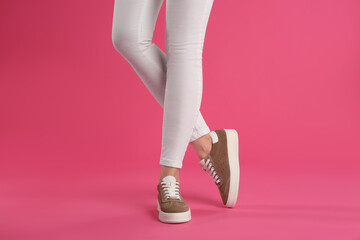 Woman wearing shoes on pink background, closeup