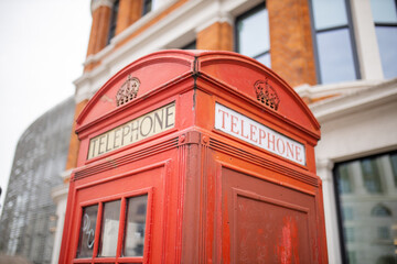 Close up of the top of a London telephone booth and a brick building behind it