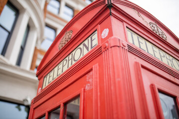Close up of the top of a London telephone booth and a brick building behind it - obrazy, fototapety, plakaty