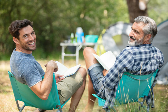 father and son camping together reading books