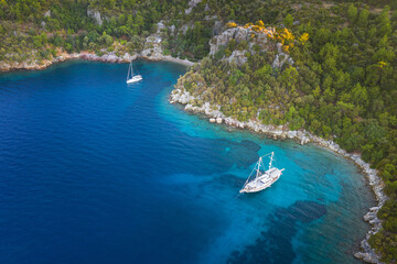 Obraz premium aerial view to curved bay with two sailing yachts with copy space