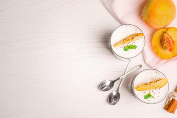 Tasty peach dessert with yogurt and chia seeds served on white wooden table, flat lay. Space for text