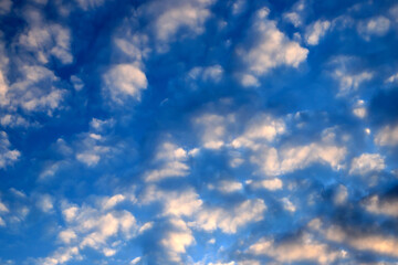 Beautiful white and pink unusual cumulus clouds against the blue sky. Picturesque, fantastic clouds, landscape background for summer, autumn, climate change, global warming.