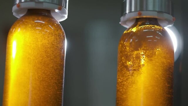 Bottling wine by the machine into bottles made of brown glass. Close up slow motion