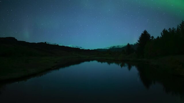 Aurora and stars mirror reflection in calm water Thingvellir Iceland extended