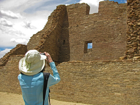 A female photographer shoots a photo of Pueblo Bonito Anasazi stone wall ruins in Chaco Canyon National Historical Park, New Mexico.