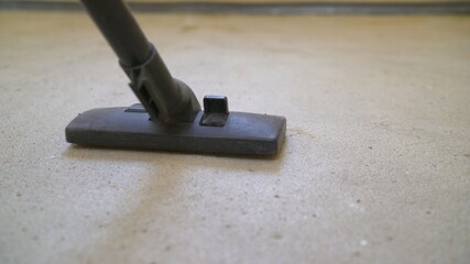 Close-up of thoroughly vacuums the concrete floor. A worker vacuums the floor from industrial concrete dust and cement mud during home renovation