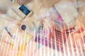 Multi exposure of man's hands typing over computer keyboard and forex graph hologram drawing. Top...