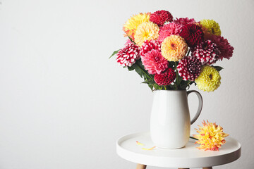 Obraz na płótnie Canvas Bouquet of beautiful dahlia flowers on table near white wall. Space for text