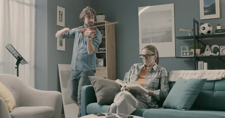 Woman annoyed by her husband playing violin at home - Powered by Adobe