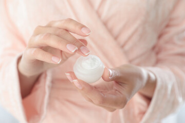 Young woman holding jar of cream closeup