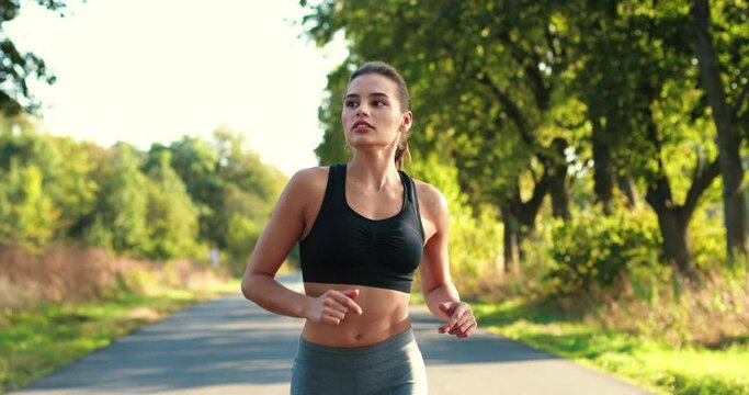 Portrait of fit Caucasian sportswoman in sportswear doing exercises for weight loss and running outdoor. Beautiful concentrated young female training. Sporty lifestyle. Workout concept