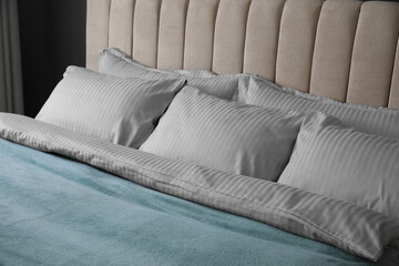 Comfortable bed with soft blanket and pillows indoors, closeup