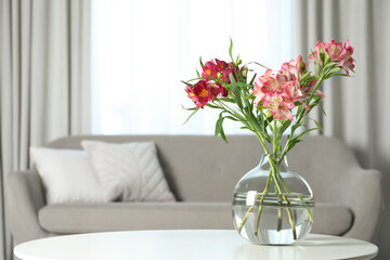 Vase with beautiful alstroemeria flowers on table in living room, space for text. Stylish element of interior design